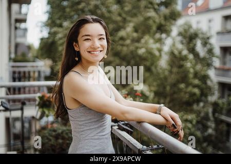 Porträt einer glücklichen jungen Frau, die auf dem Balkon steht Stockfoto