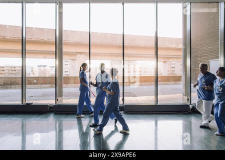 Multirassische Mitarbeiter sprechen während sie im Flur des Krankenhauses laufen Stockfoto