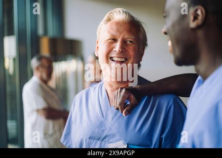 Glückliche multirassische männliche Ärzte, die im Krankenhaus sprechen Stockfoto