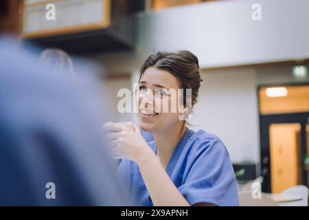 Lächelnde Ärztin mit Kollegin in der Kantine im Krankenhaus Stockfoto