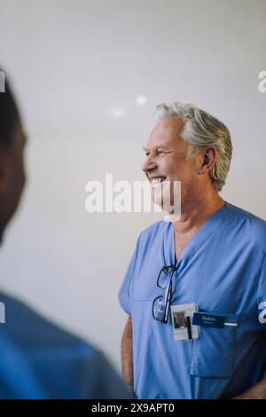 Glücklicher Oberarzt, der vor der Wand steht Stockfoto