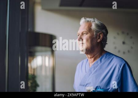 Nachdenklicher Oberarzt in blauem Peeling im Krankenhaus Stockfoto
