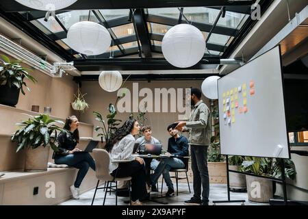 Männlicher Unternehmer, der Geschäftsstrategien mit Kollegen im Coworking Space plant Stockfoto