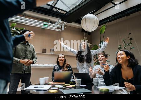 Fröhliche Geschäftsleute feiern während des Teammeetings im Büro Stockfoto