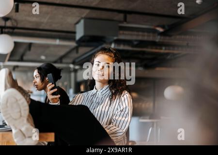 Porträt einer lächelnden Unternehmerin, die im Büro mit den Füßen nach oben am Schreibtisch sitzt Stockfoto