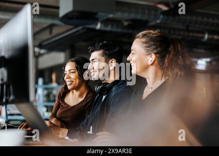 Lächelnde Computerprogrammierer, die im Büro am Computer arbeiten Stockfoto