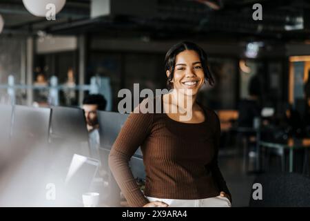 Porträt einer jungen lächelnden Geschäftsfrau, die sich im Büro beugt Stockfoto