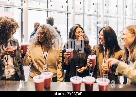 Glückliche weibliche Delegierte, die während der Pausen im Convention Center Smoothies trinken Stockfoto