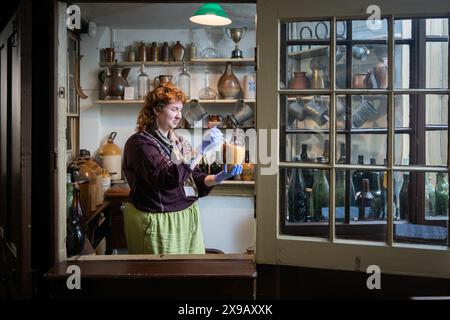 Cambridge, Großbritannien. 30. Mai 2024. Collections Officer Beau Brannick reinigt eine alte Kanne in der ursprünglichen Bar des White Horse Inn, heute Museum of Cambridge. Das Gebäude ist ein denkmalgeschütztes ehemaliges kutschenhaus aus dem 16. Jahrhundert. Das Museum zeigt die Geschichte und das Erbe von Cambridgeshire und die Pflege von Exponaten ist eine wichtige Aufgabe. Quelle: Julian Eales/Alamy Live News Stockfoto