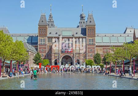 Amsterdam, Niederlande - 15. Mai 2018: Touristen in Shalow Pool Water Big Letters und Rijksmuseum Museum am Tag der heißen Quelle. Stockfoto