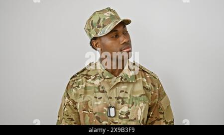 Ein afroamerikanischer Soldat in Tarnuniform steht vor weißem Hintergrund und strahlt Vertrauen und Stolz aus. Stockfoto