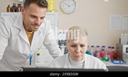 Ein Mann und eine Frau in Labormänteln arbeiten in einem Labor zusammen und konzentrieren sich intensiv auf wissenschaftliche Forschung. Stockfoto