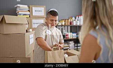 Der junge, gutaussehende latin-Mann ist ein inspirierendes Porträt, der gerne freiwillig im Wohltätigkeitszentrum arbeitet, selbstbewusst lächelt, während er steht, hält und großzügig spendet Stockfoto