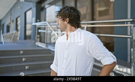 Gutaussehender Mann mit Bart in weißem Hemd, der nachdenklich auf der Straße der Stadt steht Stockfoto