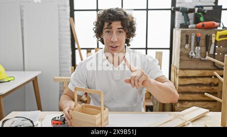 Ein junger hispanischer Mann mit lockigen Haaren arbeitet in einer gut ausgestatteten Werkstatt mit Holzarbeiten. Stockfoto