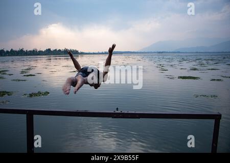 Srinagar, Jammu Und Kaschmir, Indien. 30. Mai 2024. Ein Junge springt in den Dal Lake, um sich an einem heißen Sommertag in Srinagar von der Hitze zu erholen. (Credit Image: © Adil Abass/ZUMA Press Wire) NUR REDAKTIONELLE VERWENDUNG! Nicht für kommerzielle ZWECKE! Stockfoto