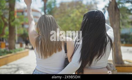 Zwei Frauen umarmen sich in einem sonnigen Stadtpark und zeigen Freundschaft und Zweisamkeit. Stockfoto