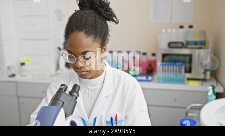 Eine afrikanische Wissenschaftlerin untersucht Proben mit einem Mikroskop in einem Labor und zeigt die Forschung im Gesundheitswesen. Stockfoto