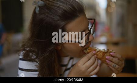 Die junge hispanische Frau genießt eine Pizza auf einer Restaurantterrasse in italien. Stockfoto