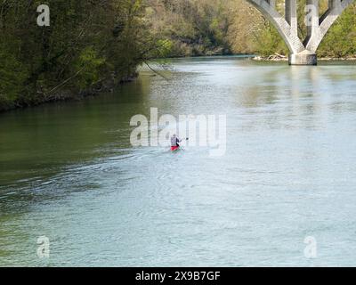 Einsame Kajakfahrer paddeln auf der Arve in Richtung Zusammenfluss mit der Rhone. Bei der Verschmelzung der Flüsse fließen sie unter ein Eisenbahnviadukt in Genf, CH. Stockfoto