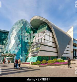 Baku, Aserbaidschan - 10. Mai 2024: Nur wenige Menschen laufen in der Nähe des modernen Designs der Park Bulvar Mall, an einem sonnigen Tag mit klarem blauem Himmel über dem Himmel Stockfoto