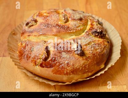 Hausgemachtes süßes Osterbrot in Backpapier auf Holztablett Stockfoto