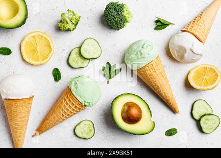 Grüne Avocado-Kokos-Eiskugeln in Waffelkegeln auf weiß, Blick von oben. Trendiges veganes Eis mit grünem Gemüse: Gurke, Brokkoli, Avocado, Stockfoto