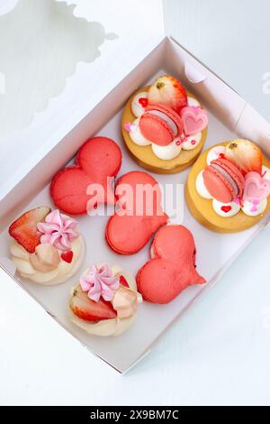 Gebäckset zum Valentinstag oder für jeden romantischen Tag, verpackt in einer Pappschachtel. Herzförmige Makronen und Mini-Kuchen Stockfoto