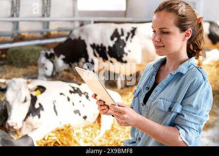 Eine Viehzüchterin arbeitet auf einem Tablet-Computer in einer Viehzucht. Stockfoto