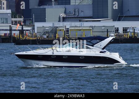 Portsmouth, England, 12. Mai 2024. Blick vom Gosport Harbour: Ein weißes, schwarz-blaues Motorboot auf ruhigem Wasser im Hafen. Stockfoto