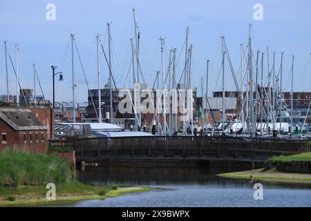 Gosport, Hampshire, England. 17. Mai 2024. Eine kleine Fußgängerbrücke neben der Stadtmauer mit Segelbootmasten im Hintergrund von Schiffen, die in Haslar Marina angedockt sind. Stockfoto