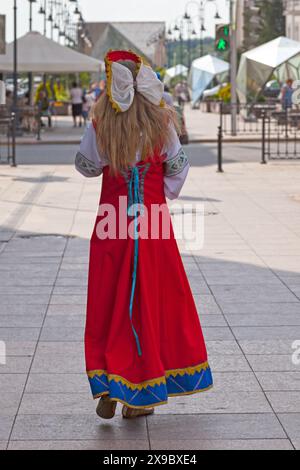 Junge Frau in traditioneller Kleidung, die in einer Straße des Stadtzentrums von Omsk, Russland, läuft. Stockfoto