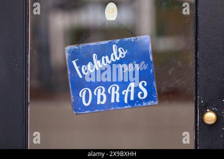 Blaues offenes Schild mit portugiesischem Schriftzug „Fechado para obras“, was auf Englisch „geschlossen für Feiertage“ bedeutet. Stockfoto