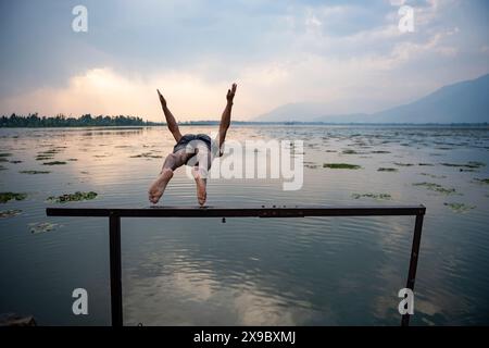 Ein Mann taucht in den Dal Lake, um sich an einem heißen Abend abzukühlen. Eine Rekordhitzewelle hat die indische Hauptstadtregion Delhi und Gebiete in den nordwestlichen und zentralen Regionen des Landes erfasst, wobei die Temperaturen während der ganzen Woche nahezu auf Allzeithochsen lagen. Stockfoto