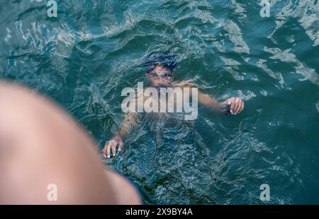 30. Mai 2024, Srinagar, Jammu & Kashmir, Indien: Ein Mann kühlt sich bei einem Schwimmen im Dal Lake an einem heißen Sommerabend ab. Eine Rekordhitzewelle hat die indische Hauptstadt Delhi und Gebiete im Nordwesten und in den zentralen Regionen des Landes überschwemmt, wobei die Temperaturen während der ganzen Woche nahezu auf Allzeithochwerten lagen. (Credit Image: © Idrees Abbas/SOPA Images via ZUMA Press Wire) NUR REDAKTIONELLE VERWENDUNG! Nicht für kommerzielle ZWECKE! Stockfoto