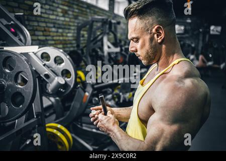 Muskelathlet trinken flüssiges Vitamin b 12 oder Ergänzung in kleiner Einweg-schwarzer Flasche, Bodybuilder-Mann mit Sporternährung in Ampule-Tropfen Stockfoto