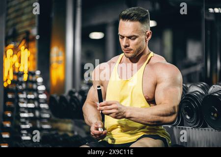 Muskelathlet trinken flüssiges Vitamin b 12 oder Ergänzung in kleiner Einweg-schwarzer Flasche, Bodybuilder-Mann mit Sporternährung in Ampule-Tropfen Stockfoto