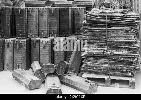 Oyster Matten und Käfige aus schwarzem Kunststoff stapeln sich im Whitstable Harbour in verschiedenen Farben und Texturen. Verkrustete Austernmatten und -Käfige. Stockfoto