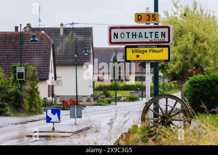 PRODUKTION - 29. Mai 2024, Frankreich, Nothalten: Das Stadtzeichen Nothalten steht am Ortseingang und trägt auch einen Aufkleber mit der Inschrift „im ELSASS“. Die Sonderregelungen des lokalen Rechts im Elsass und Lothringen besagen, dass in den Regionen, die nach dem Ersten Weltkrieg wieder Teil Frankreichs wurden, deutsche Regelungen in einer Reihe von Bereichen des gesellschaftlichen Lebens beibehalten wurden. Das reicht vom Jagdrecht über religiöse Praxis und Krankenversicherung bis hin zu Kataster und Verbänden. Die Grenzregion hat derzeit Schwierigkeiten sicherzustellen, dass das lokale Recht im Zuge des stan nicht untergraben wird Stockfoto