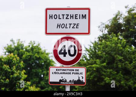 PRODUKTION - 29. Mai 2024, Frankreich, Holtzheim: Das Ortszeichen Holtzheim steht am Ortseingang und trägt auch den elsässischen Ortsnamen Holtze. In den Sonderregelungen des lokalen Rechts im Elsass und Lothringen heißt es, dass in den Regionen, die nach dem Ersten Weltkrieg wieder Teil Frankreichs wurden, deutsche Regelungen in einer Reihe von Bereichen des gesellschaftlichen Lebens beibehalten wurden. Das reicht vom Jagdrecht über religiöse Praxis und Krankenversicherung bis hin zu Kataster und Verbänden. Die Grenzregion hat derzeit Schwierigkeiten, dafür zu sorgen, dass das lokale Recht nicht im Laufe der t untergraben wird Stockfoto