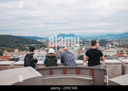 Touristen stehen an einem bewölkten Tag auf einem Aussichtsturm auf der Burg Ljubljana in Slowenien mit Blick auf die Stadt Stockfoto