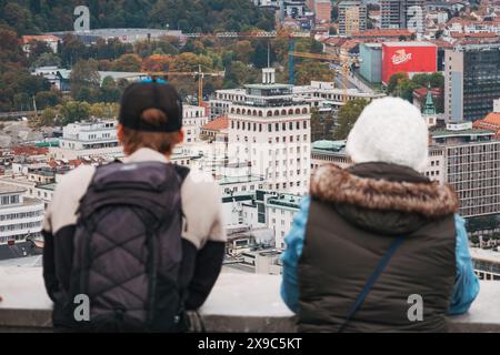 Touristen stehen an einem bewölkten Tag auf einem Aussichtsturm auf der Burg Ljubljana in Slowenien mit Blick auf die Stadt Stockfoto