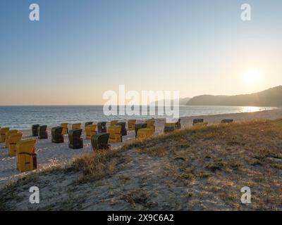 Liegestühle am Strand bei Sonnenaufgang mit ruhiger und friedlicher Atmosphäre, Herbststimmung am Strand von Binz mit Bäumen Liegen am Morgen Stockfoto