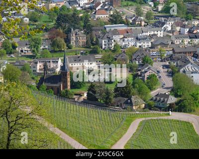 Ein malerisches Dorf mit einer Kirche und mehreren historischen Gebäuden, eingebettet in eine grüne Frühlingslandschaft, kleine Stadt an einem Fluss zwischen grünen Hügeln Stockfoto