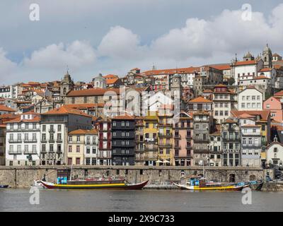 Farbenfrohe Häuser der Altstadt am Flussufer, lebhafte Stadtlandschaft mit Booten auf dem Wasser, farbenfrohe Häuser auf einem Fluss mit bunten Booten und einem Stockfoto