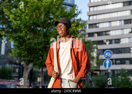 Ein selbstbewusster, stilvoller Mann mit Brille, der in der Stadt steht, wartet auf einen Freund, der lächelnd davonblickt Stockfoto