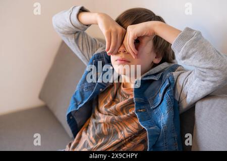 Müdes, krankes Teenager-Kind, das sich mit akademischem Druck und persönlichem Wachstum auseinandersetzt, Trost sucht in einem Moment stille Reflexion, Kindheitsstress Stockfoto