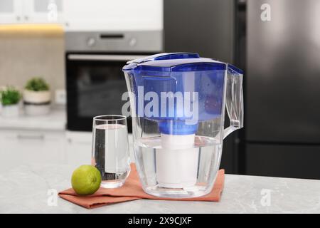 Wasserfilterkanne, Glas und Kalk auf hellem Marmortisch in der Küche, Nahaufnahme Stockfoto