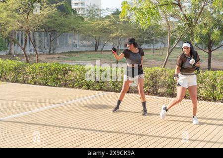 Zwei Frauen in sportlicher Kleidung trainieren gemeinsam in einem Stadtpark und nehmen an einem sonnigen Tag an einem dynamischen Outdoor-Workout Teil. Stockfoto