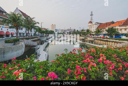 Jakarta, Indonesien - 7. Mai 2024. Ein malerischer Kanal schlängelt sich durch ein historisches Stadtzentrum, gesäumt von lebendigen Blumen und farbenfrohen Gebäuden mit Tradition Stockfoto